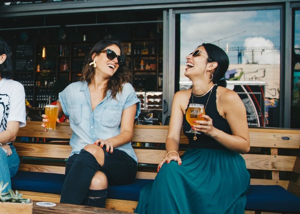 two smiling women sitting on wooden bench 1267696